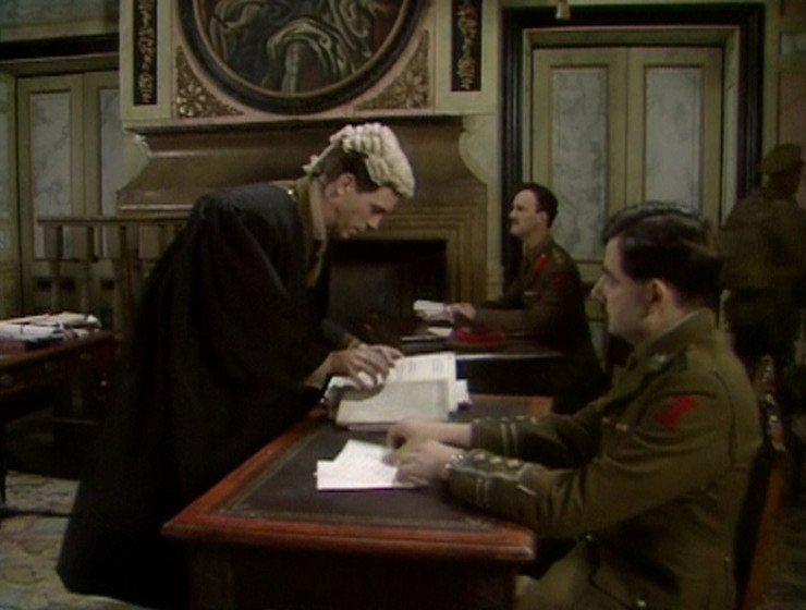 George and Blackadder in the courtroom, with the circular portrait in the background