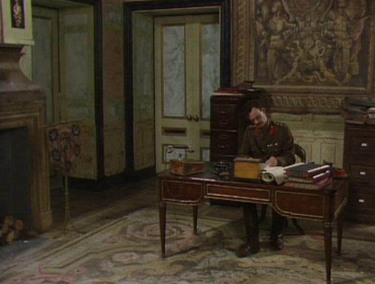 Darling in Melchett's office, with the tapestry behind him