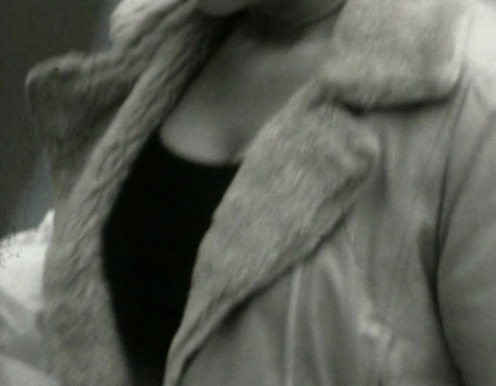 Black and white: close-up of woman's chest, wearing sheepskin coat or similar