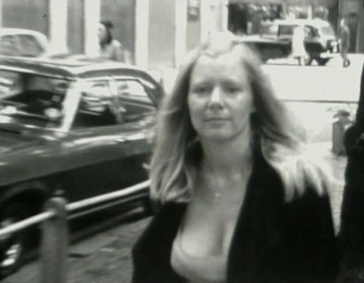 Black and white: woman with cleavage in street, looking at camera