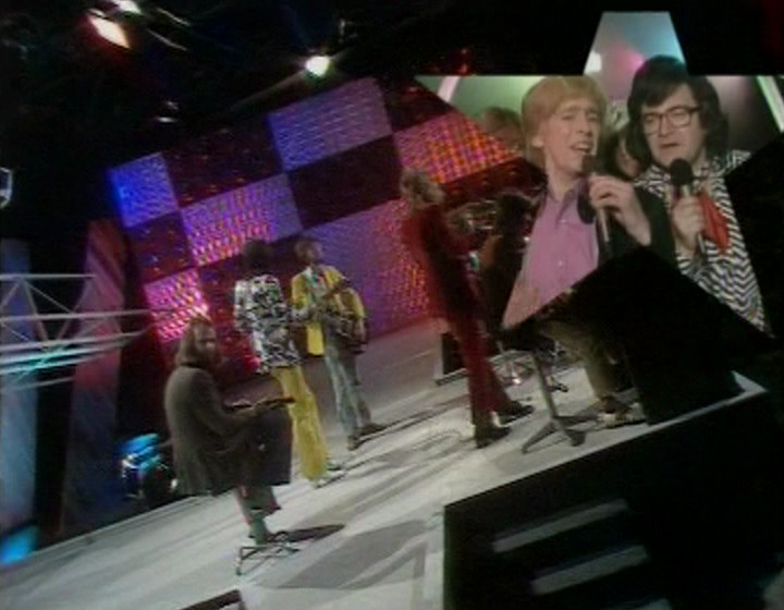 Wide shot of Rod Stewart with Smashie and Nicey in the corner