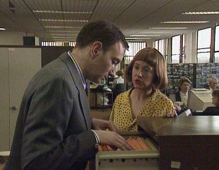 Simon Day as Andy at a filing cabinet, with Arabella Weir as Ruth