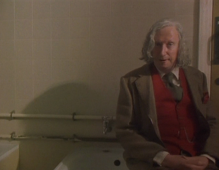 Mr Kipling sitting on the edge of a bath in a communal bathroom