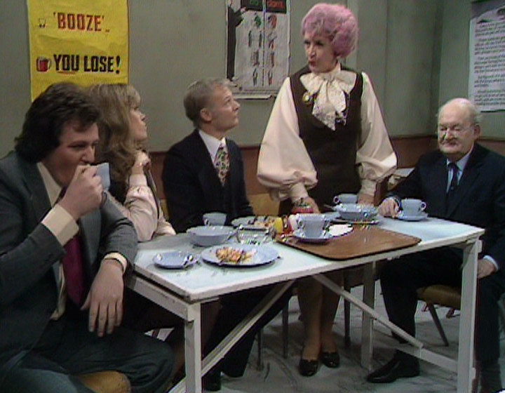 The Are You Being Served? gang around a table in the canteen, with a gap around one side, from a slightly different angle